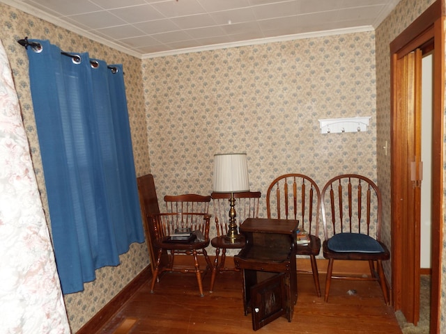 living area with wallpapered walls, crown molding, baseboards, and wood finished floors