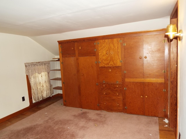 unfurnished bedroom with a closet, baseboards, carpet flooring, and vaulted ceiling