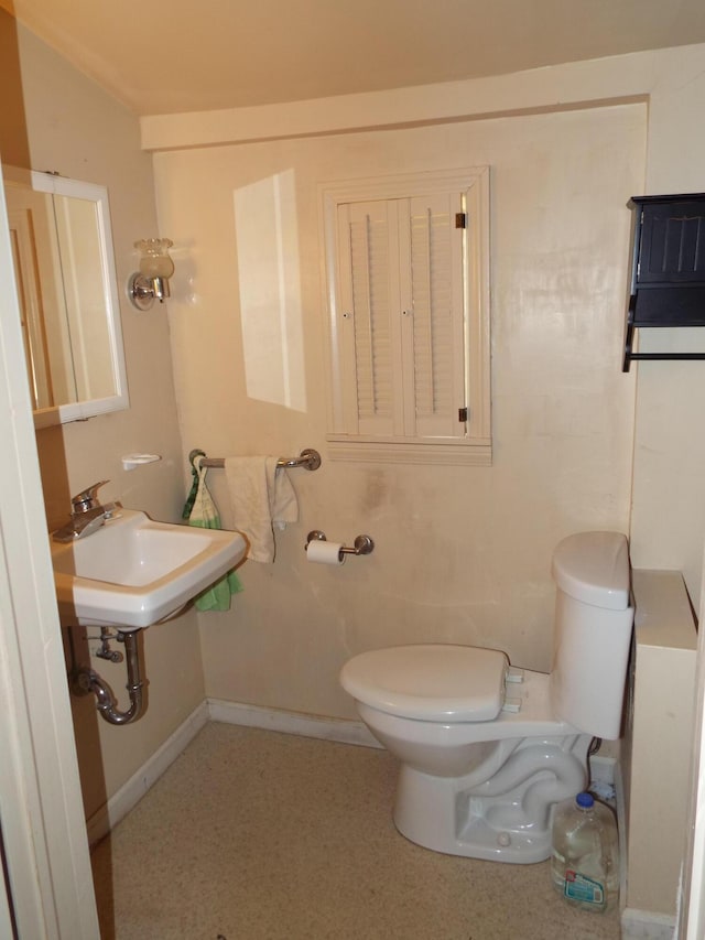 bathroom featuring a sink, baseboards, and toilet