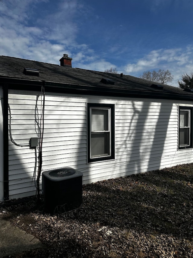 view of property exterior featuring central air condition unit and a chimney