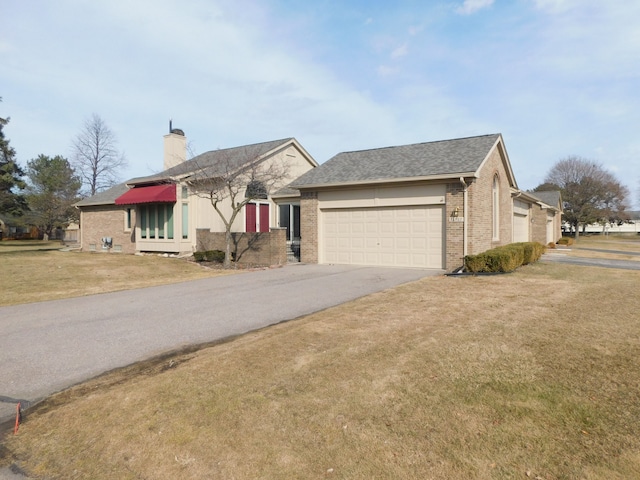 ranch-style house with aphalt driveway, an attached garage, a front yard, and brick siding