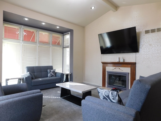 living area with carpet, visible vents, lofted ceiling with beams, plenty of natural light, and a glass covered fireplace