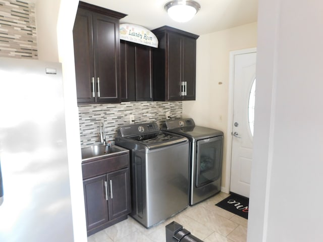 clothes washing area featuring washing machine and dryer, light tile patterned flooring, cabinet space, and a sink