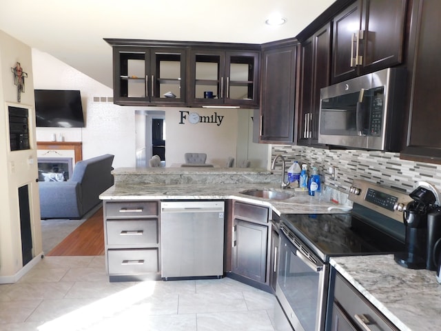 kitchen featuring light stone counters, backsplash, appliances with stainless steel finishes, and a sink