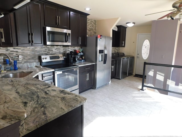 kitchen with light stone counters, separate washer and dryer, a sink, ceiling fan, and stainless steel appliances