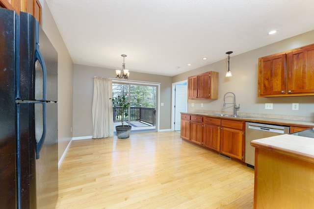 kitchen featuring a sink, light wood-type flooring, freestanding refrigerator, a notable chandelier, and stainless steel dishwasher