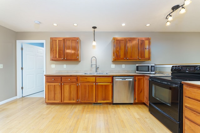 kitchen featuring brown cabinetry, a sink, light countertops, light wood-style floors, and appliances with stainless steel finishes