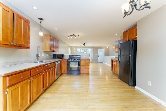 kitchen with black appliances, a sink, a peninsula, light wood finished floors, and light countertops