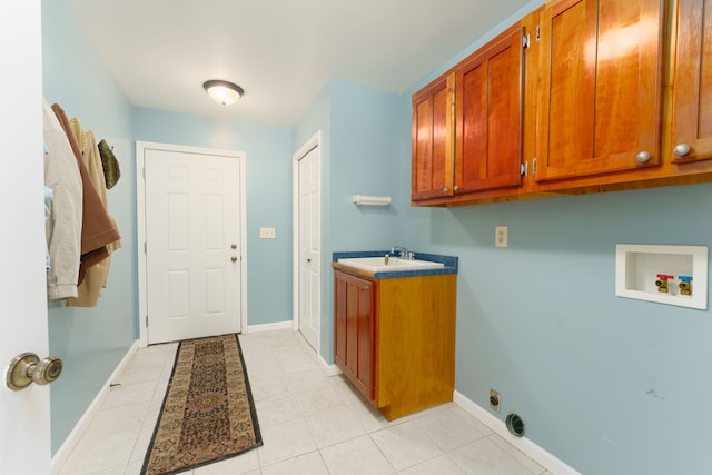 washroom with a sink, baseboards, cabinet space, and washer hookup