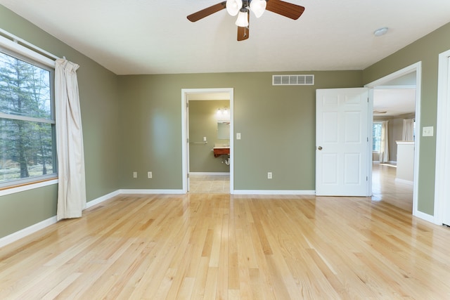 empty room with visible vents, light wood-style flooring, baseboards, and ceiling fan