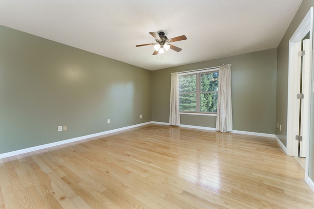 spare room featuring baseboards, ceiling fan, and light wood finished floors