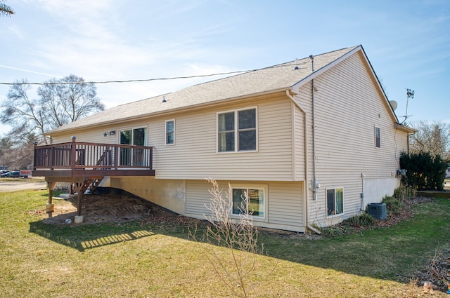 rear view of property featuring central air condition unit, a lawn, roof with shingles, and a wooden deck