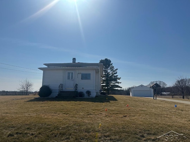 back of property with a yard, a detached garage, an outbuilding, and entry steps