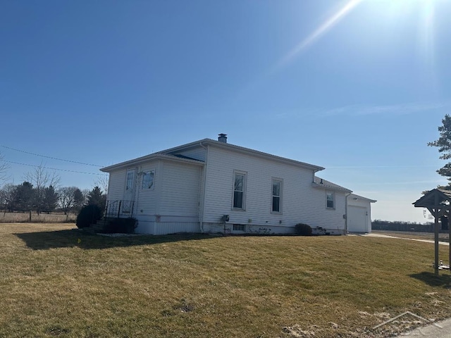 view of side of property with a yard, a garage, and a chimney