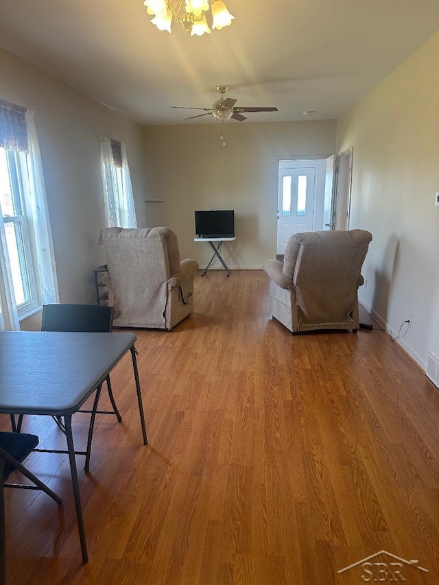 living room with a ceiling fan, visible vents, light wood-type flooring, and baseboards