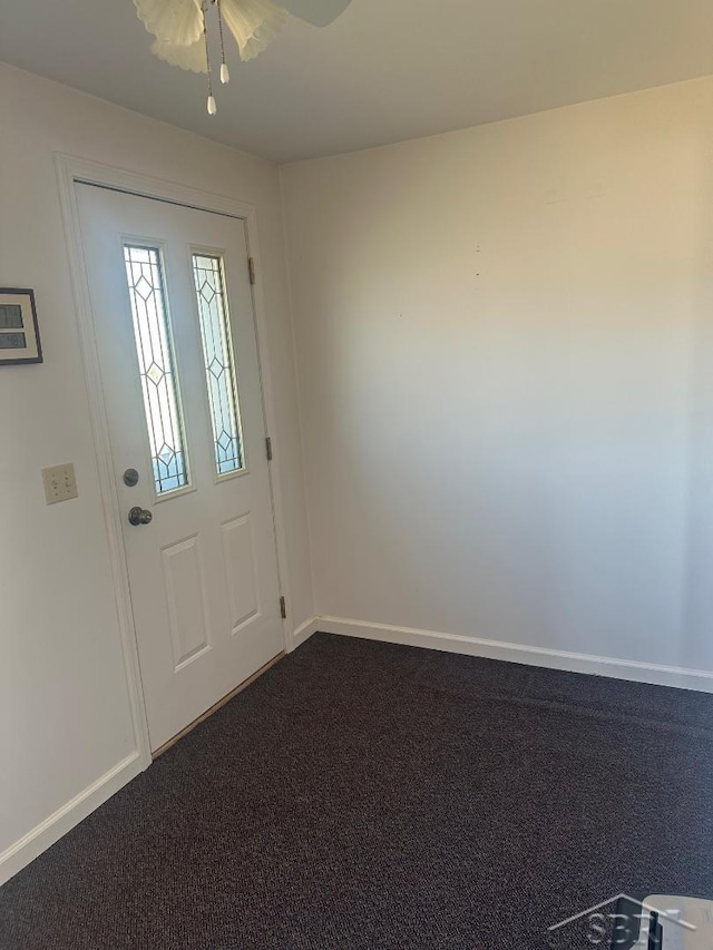 foyer entrance featuring a ceiling fan, baseboards, and dark colored carpet