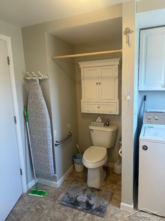 bathroom featuring baseboards, washer / clothes dryer, and toilet