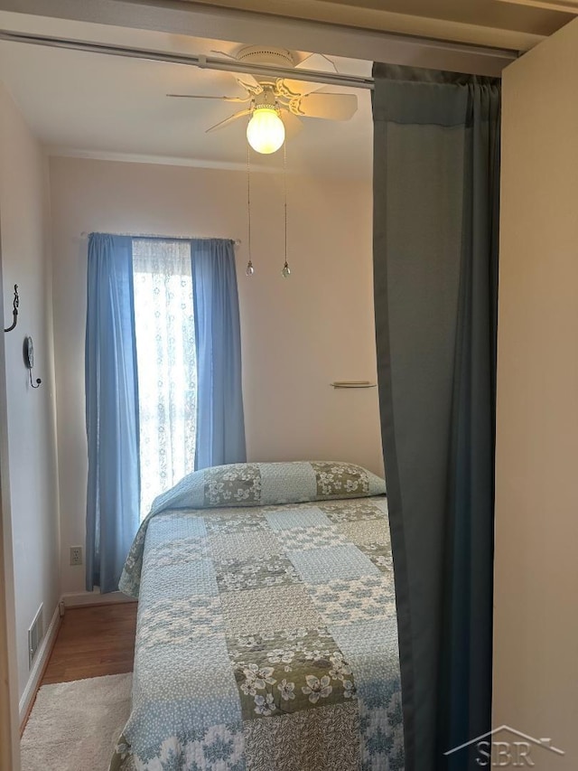 bedroom with a ceiling fan, wood finished floors, and visible vents