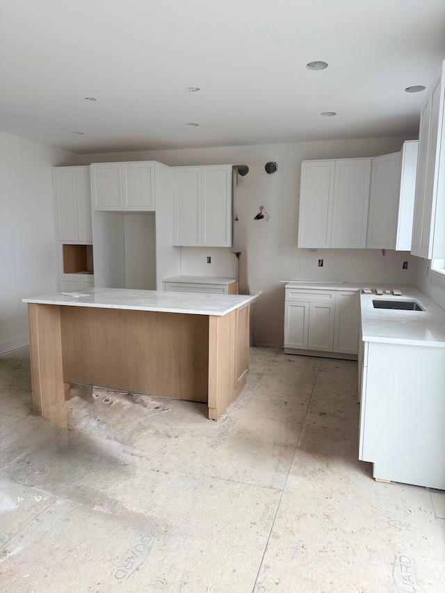 kitchen with white cabinets, a kitchen island, and a sink
