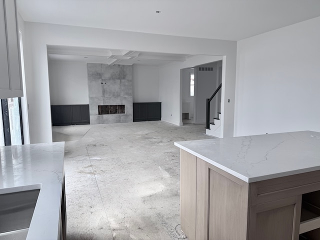 unfurnished living room featuring stairs, a tiled fireplace, and visible vents