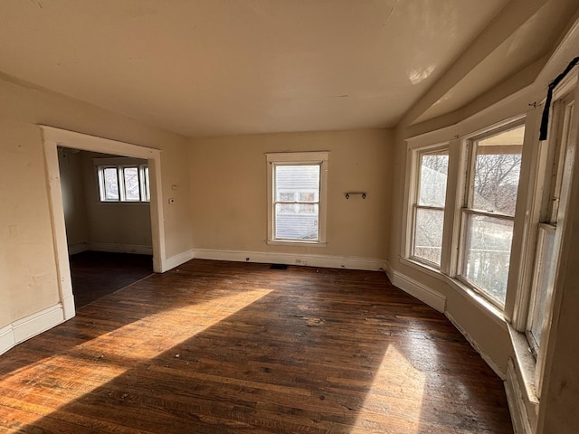 spare room featuring visible vents, baseboards, dark wood-type flooring, and vaulted ceiling