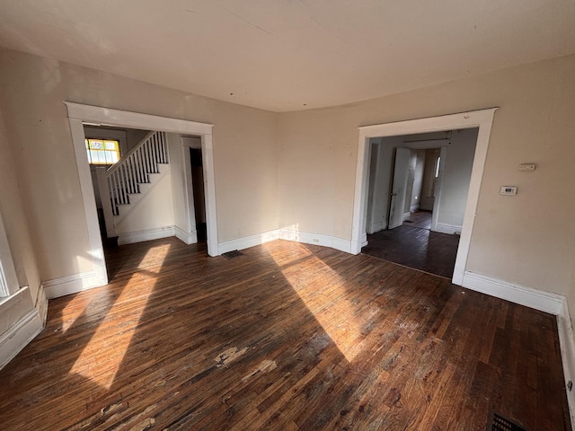 unfurnished room featuring stairway, visible vents, dark wood-type flooring, and baseboards