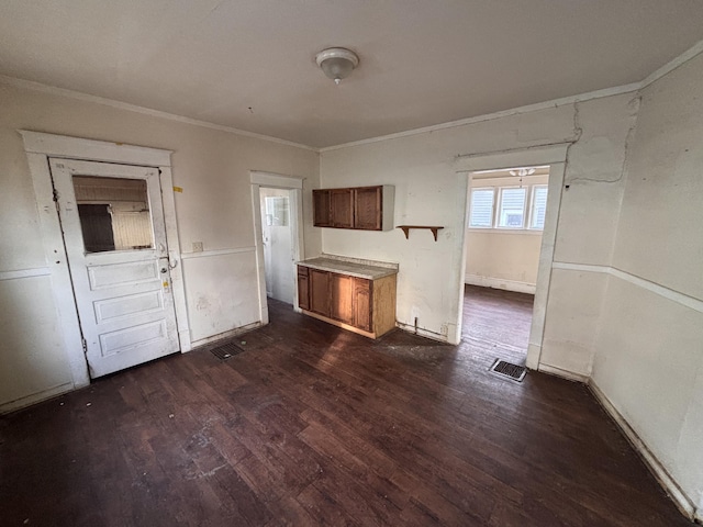 kitchen with brown cabinetry, visible vents, dark wood finished floors, ornamental molding, and light countertops