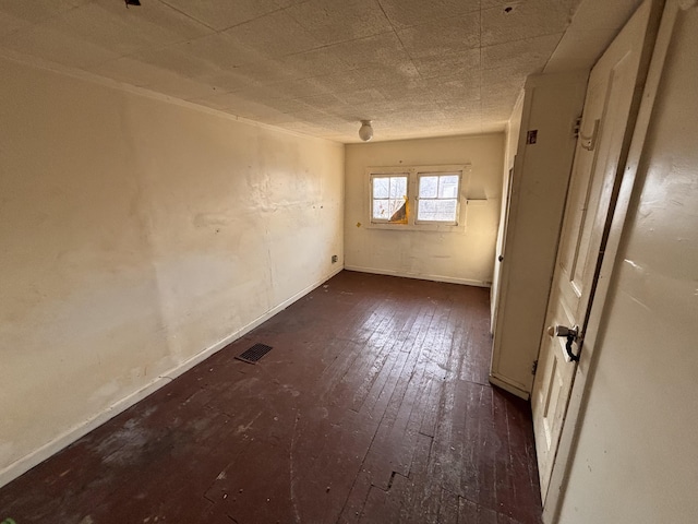 unfurnished room featuring visible vents, baseboards, and dark wood-style flooring