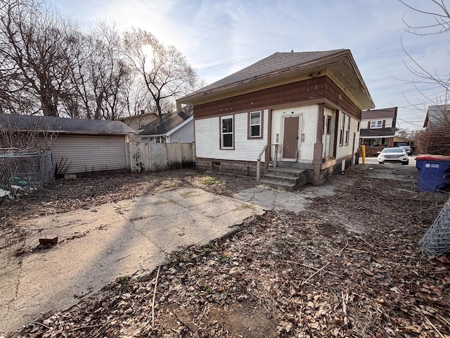 rear view of property with fence and a shingled roof