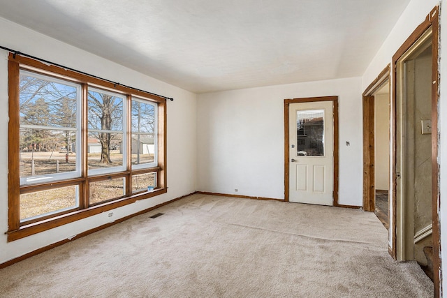 unfurnished room featuring visible vents, light carpet, and baseboards