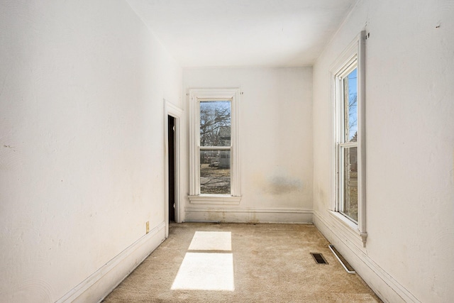 empty room featuring visible vents and light colored carpet