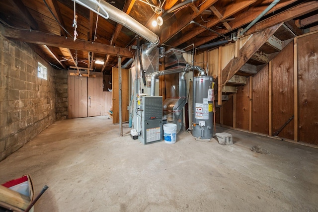 below grade area featuring gas water heater, heating unit, and concrete block wall