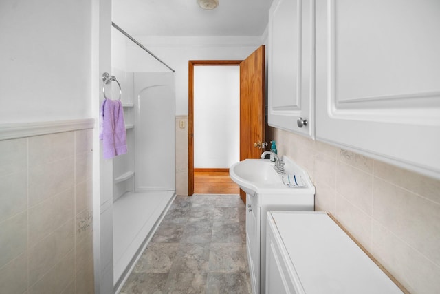 bathroom with vanity, a shower stall, stone finish floor, and tile walls