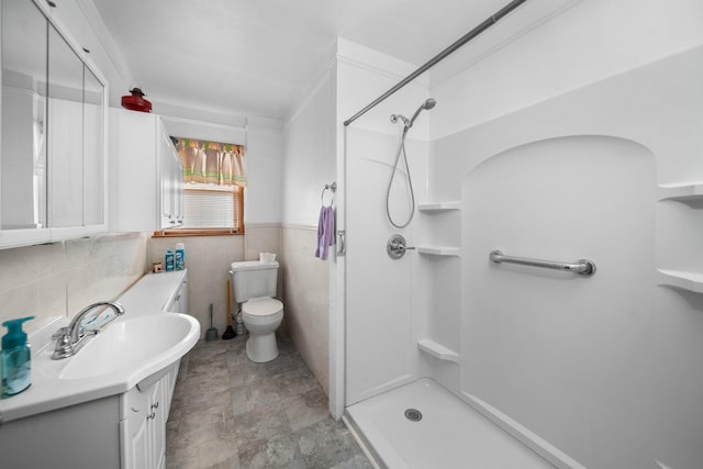 full bathroom with vanity, a wainscoted wall, a stall shower, tile walls, and toilet