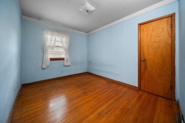 unfurnished room featuring hardwood / wood-style floors, baseboards, and ornamental molding