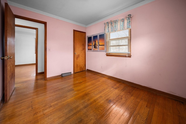 unfurnished room with baseboards, wood-type flooring, and ornamental molding