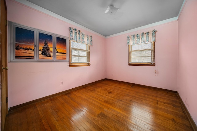 spare room featuring baseboards, wood-type flooring, and ornamental molding