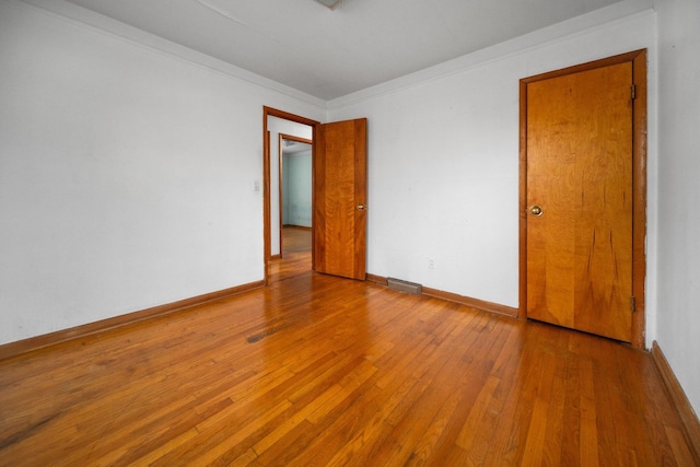 spare room with visible vents, crown molding, baseboards, and wood-type flooring