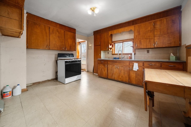 kitchen featuring a sink, light countertops, white gas range oven, brown cabinets, and backsplash