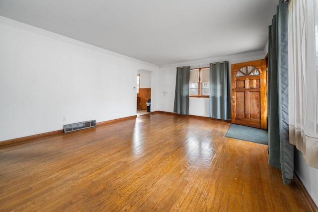 unfurnished room featuring visible vents, baseboards, crown molding, and hardwood / wood-style flooring