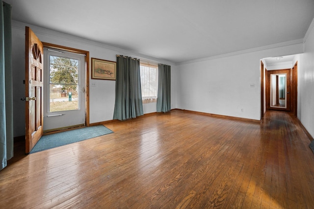 spare room featuring hardwood / wood-style flooring, crown molding, and baseboards