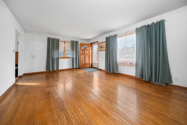 spare room featuring ornamental molding, baseboards, and hardwood / wood-style flooring