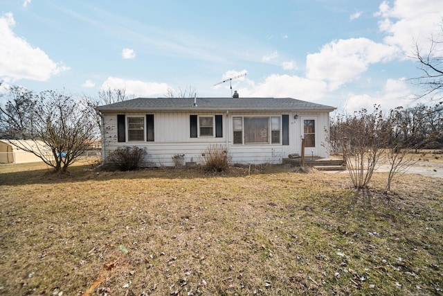 ranch-style home featuring roof with shingles and a front lawn