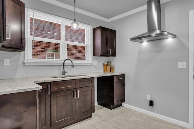 kitchen featuring baseboards, ornamental molding, a sink, dark brown cabinets, and wall chimney range hood