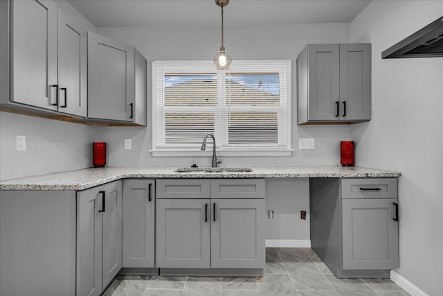 kitchen with range hood, baseboards, a sink, gray cabinetry, and decorative light fixtures