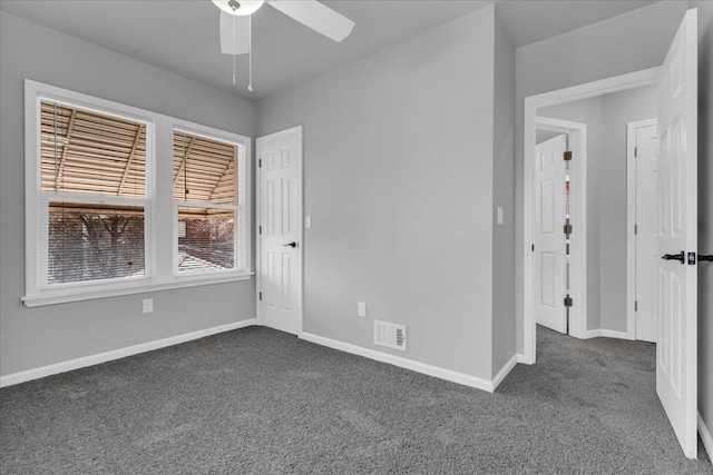 unfurnished room with visible vents, ceiling fan, baseboards, and dark colored carpet