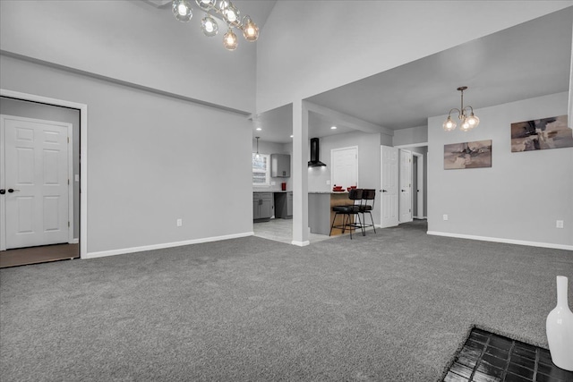 unfurnished living room with baseboards, carpet, a chandelier, recessed lighting, and a towering ceiling