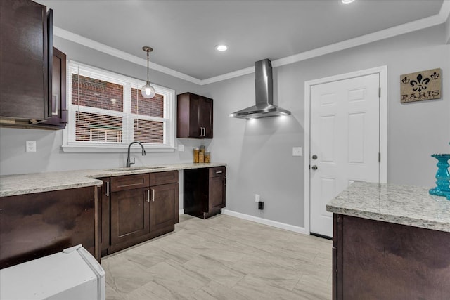 kitchen featuring baseboards, dark brown cabinetry, ornamental molding, wall chimney exhaust hood, and a sink