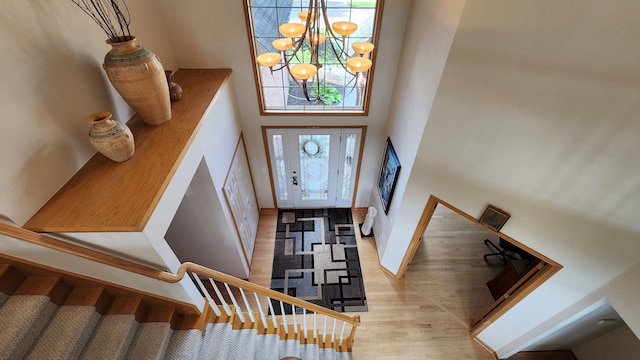 entrance foyer with wood finished floors, baseboards, stairs, a towering ceiling, and a notable chandelier