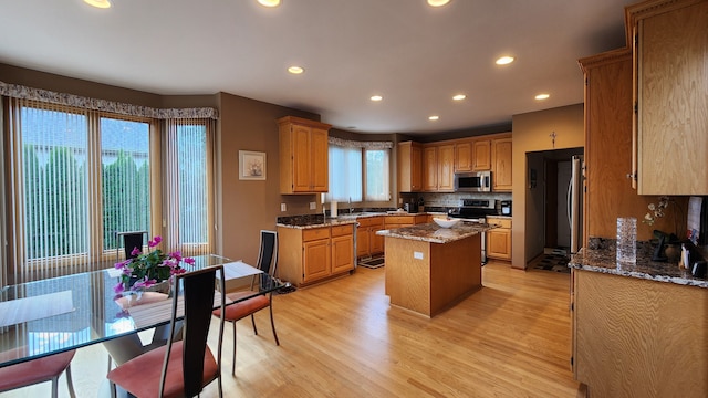 kitchen with light wood-style flooring, appliances with stainless steel finishes, a kitchen island, and a sink